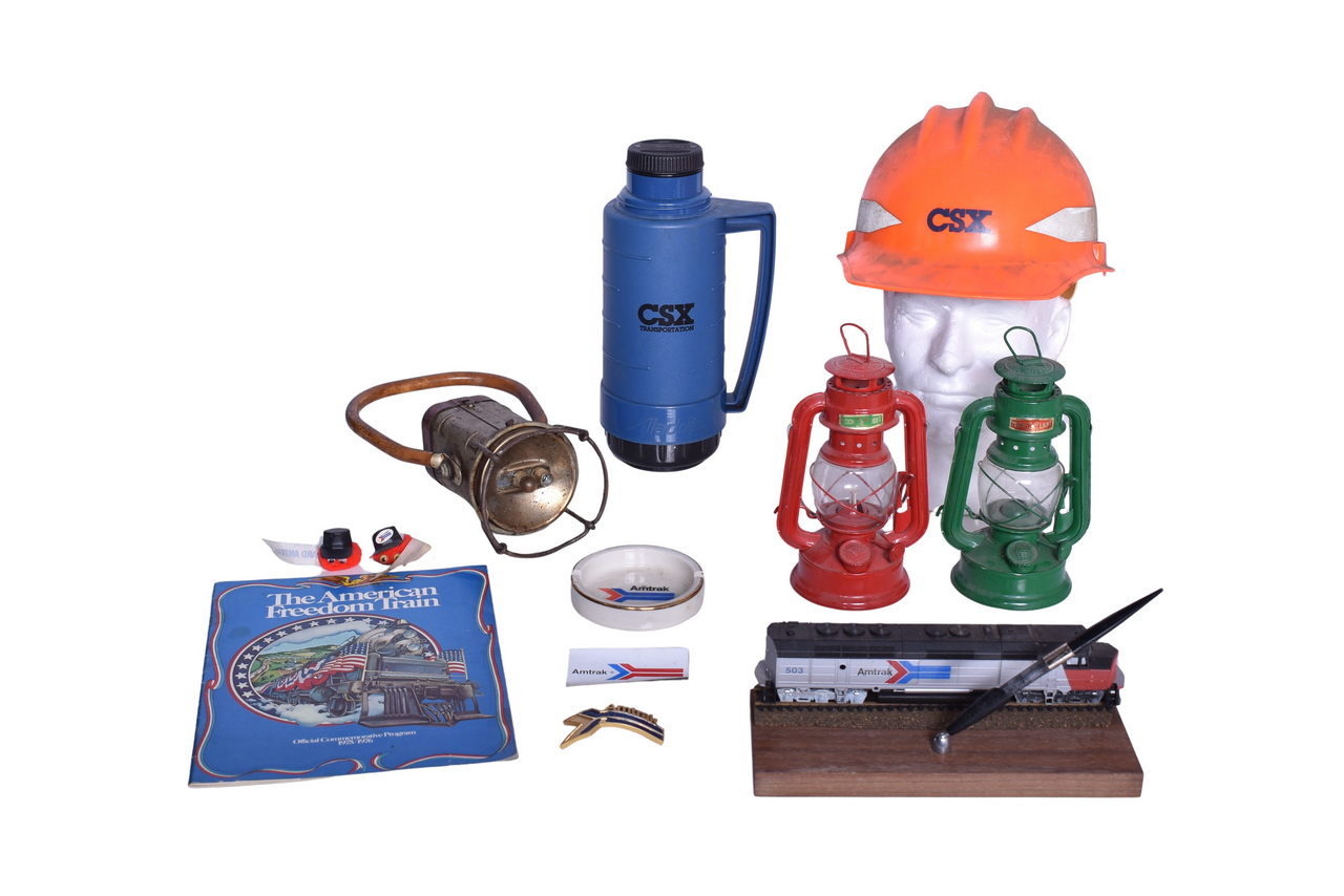 4131 - Group Of Mixed Railroad Memorabilia- Justrite Hand Held Lantern, Moon Light Oil Lamps, CSX Hard Hat, Amtrak Paper Weight And Pen Holder, etc. thumbnail